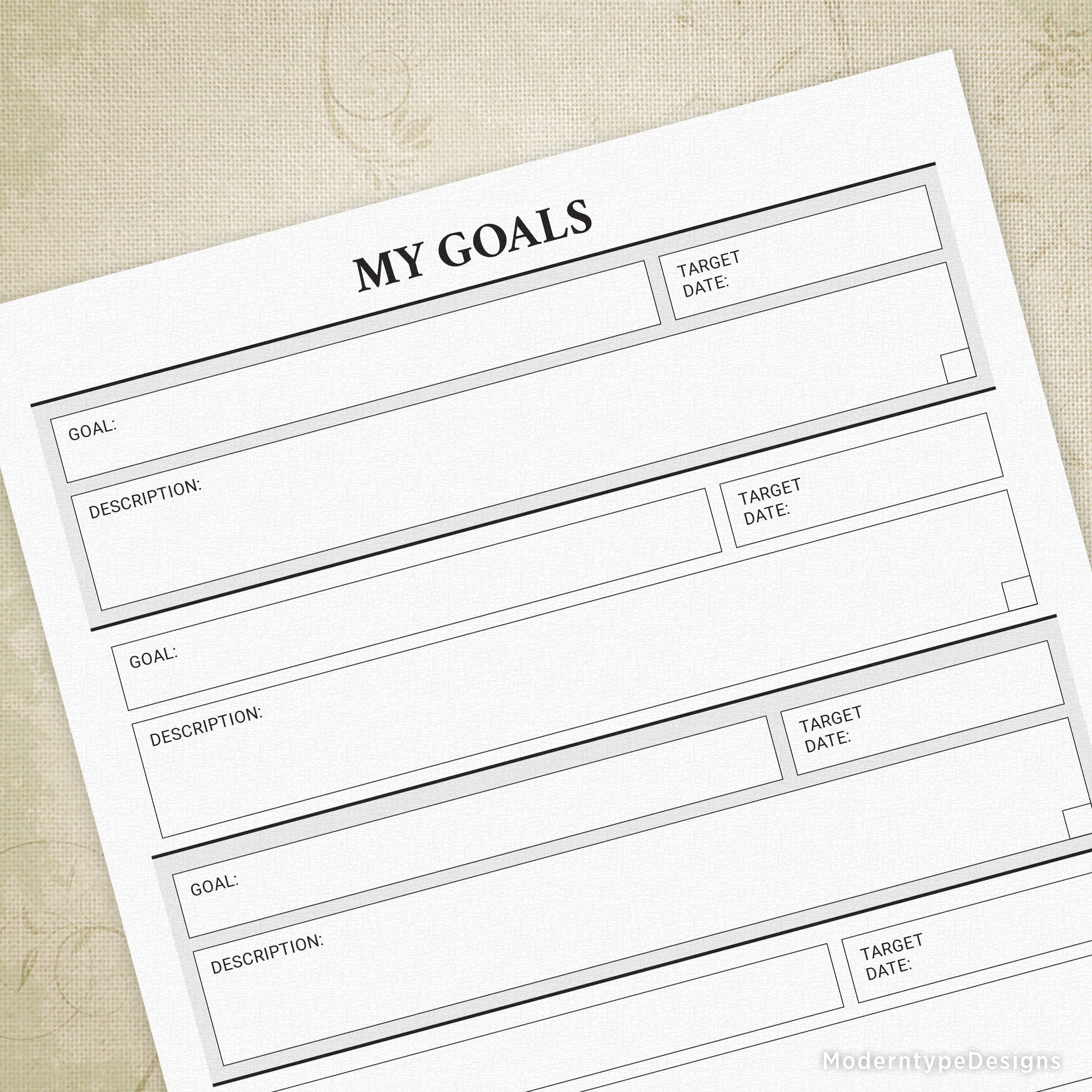 A printed sheet titled 'MY GOALS' with sections for setting and tracking personal goals, laid on a textured background.