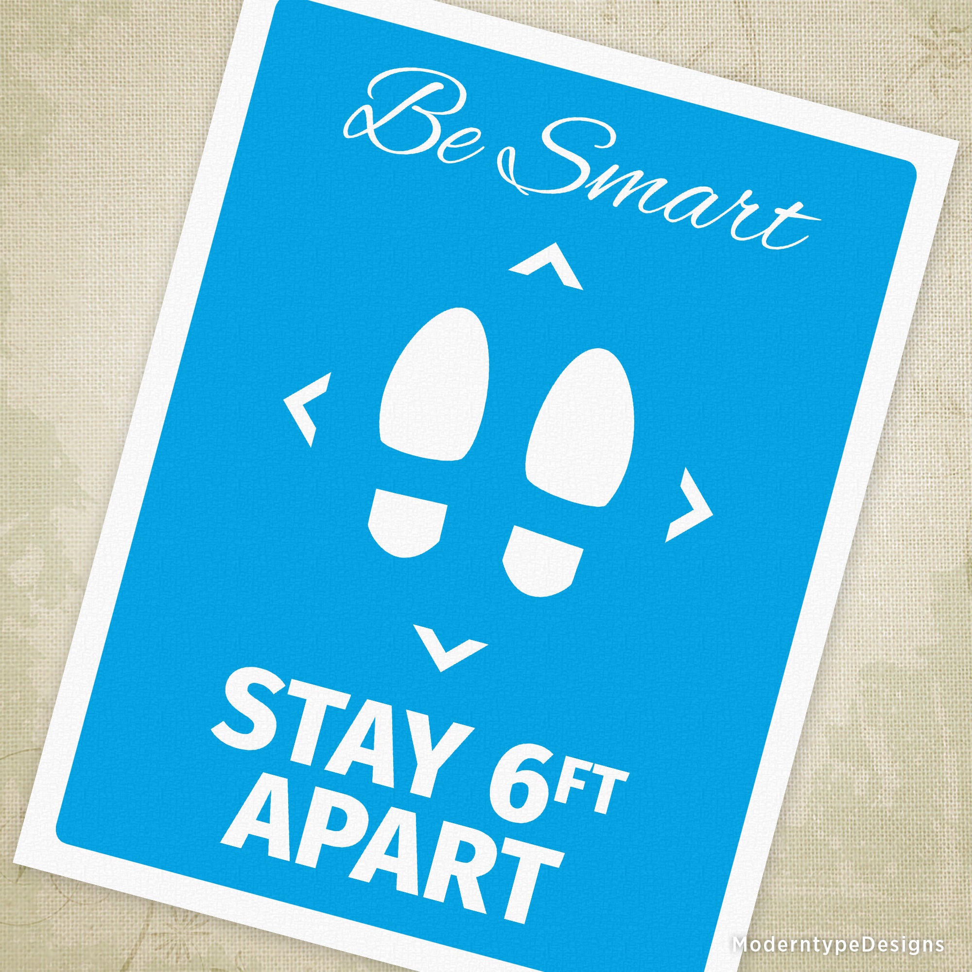 A printable sign with blue content and white margins featuring the text 'BE SMART STAY 6FT APART' and a graphic of two footprints on a blue background.